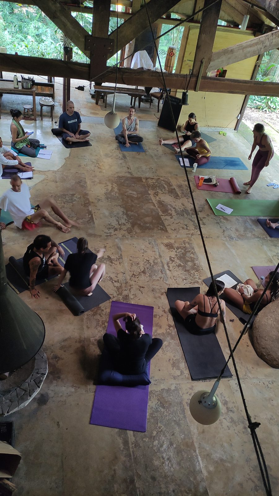 Prática coletiva de asana no salão do retiro, conduzida por professor